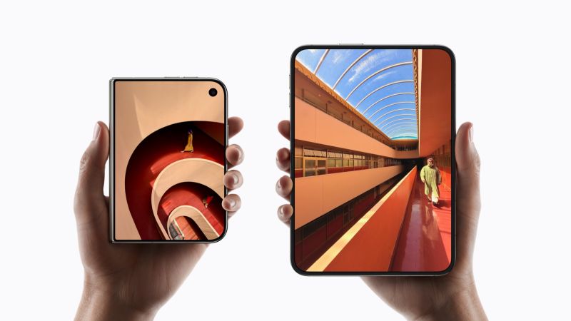 Deux mains tiennent chacune un iPhone Duo sur fond blanc : à gauche, l'appareil fermé, petit écran extérieur ; à droite, l'appareil déplié, grand écran intérieur montrant un couloir d'architecture orangé.