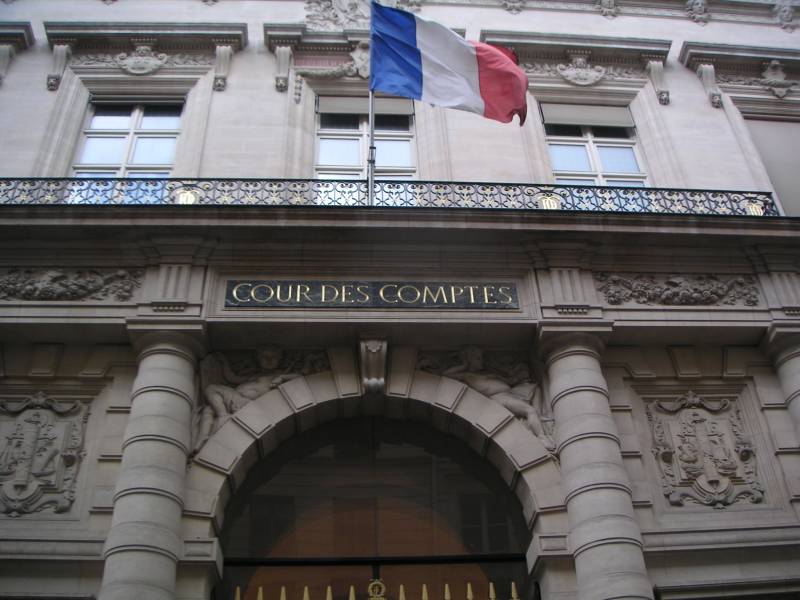 Façade en pierre sculptée, drapeau français au balcon, et au-dessus d'une porte en arc l'inscription dorée « Cour des comptes ».