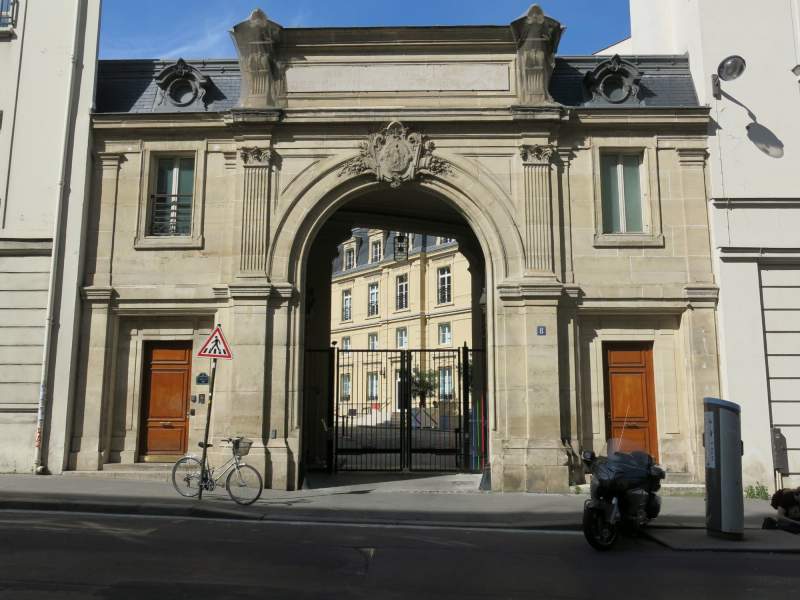 Porche en pierre du 8 rue de Londres à Paris, grille ouverte sur une cour, vélo et moto garés sur le trottoir.