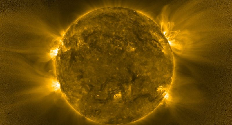 Le disque du Soleil, brun doré et marbré de zones sombres, entouré d'un halo jaune ; sur ses bords, des grappes de boucles lumineuses très brillantes, d'où partent de longs filaments diffus qui s'étirent dans l'espace.